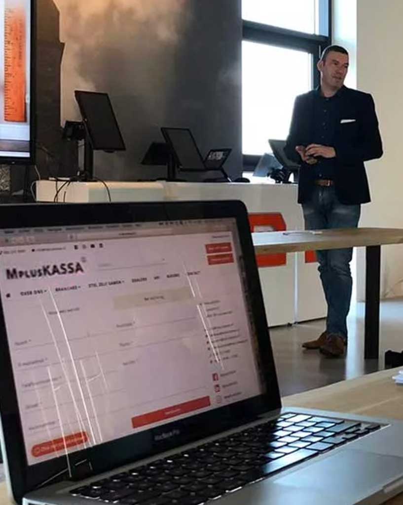 Marco Kramer licht tijdens een werksessie een analyse toe; op de laptop op de voorgrond staat een website open.